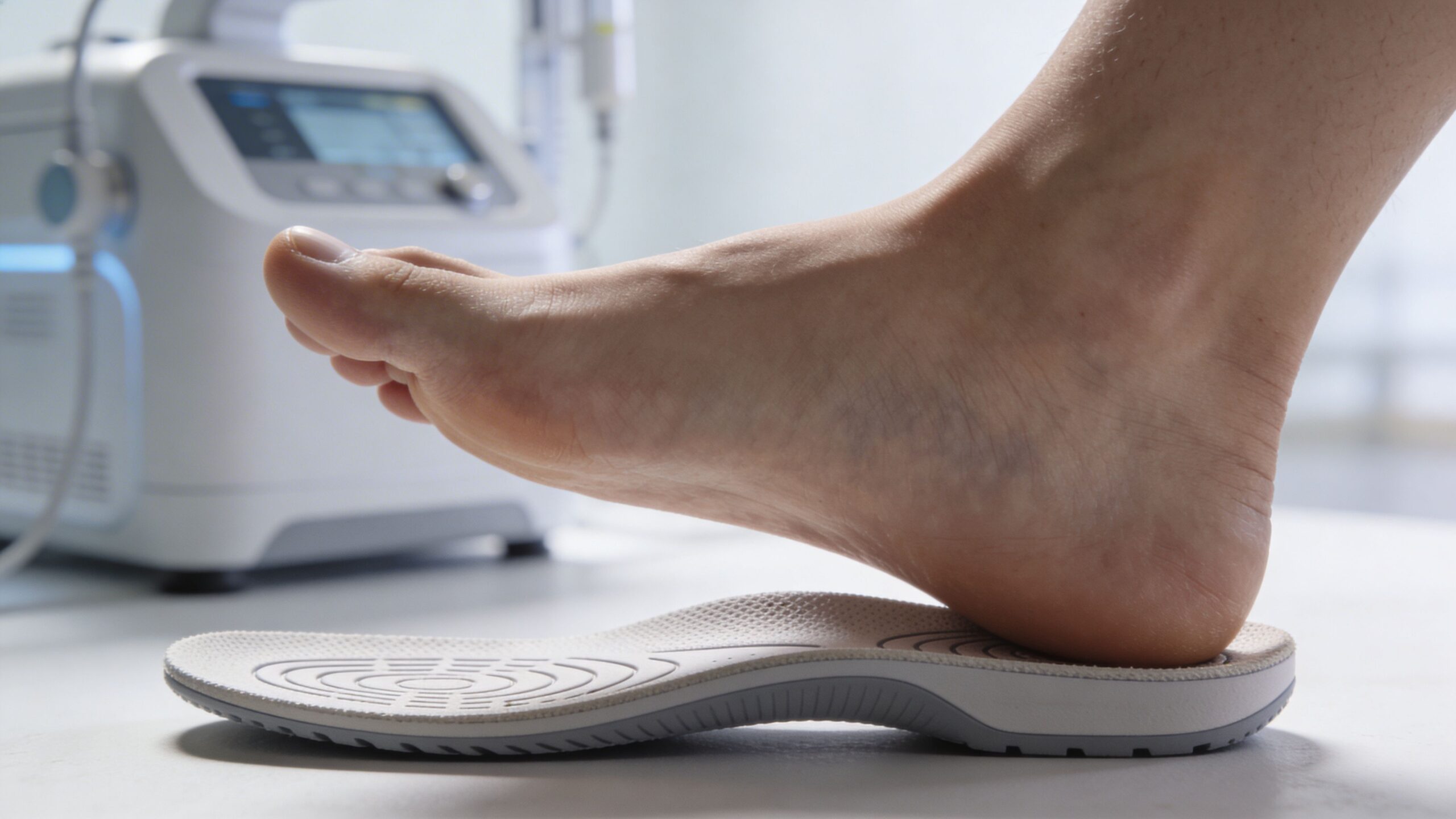 En person placerer en fod på en specialfremstillet ortopædisk indlægssål til behandling af hælspore og fodproblemer.