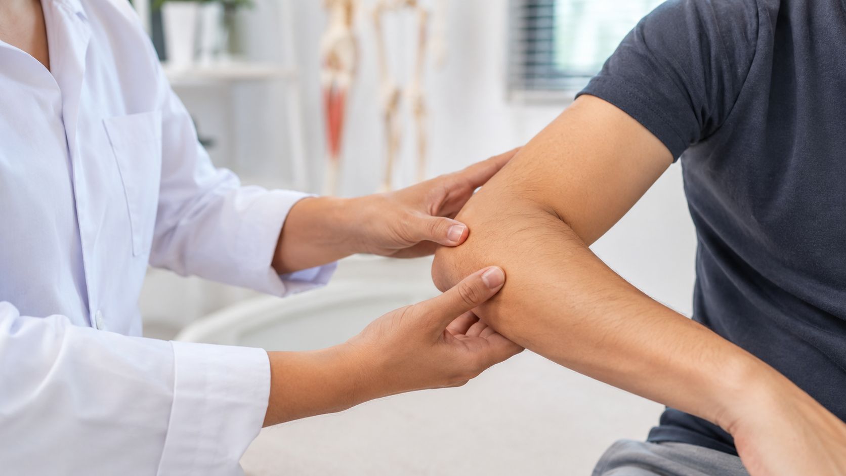 En fysioterapeut undersøger patientens albue for at vurdere symptomer på en mulig tennis- eller golfalbue.